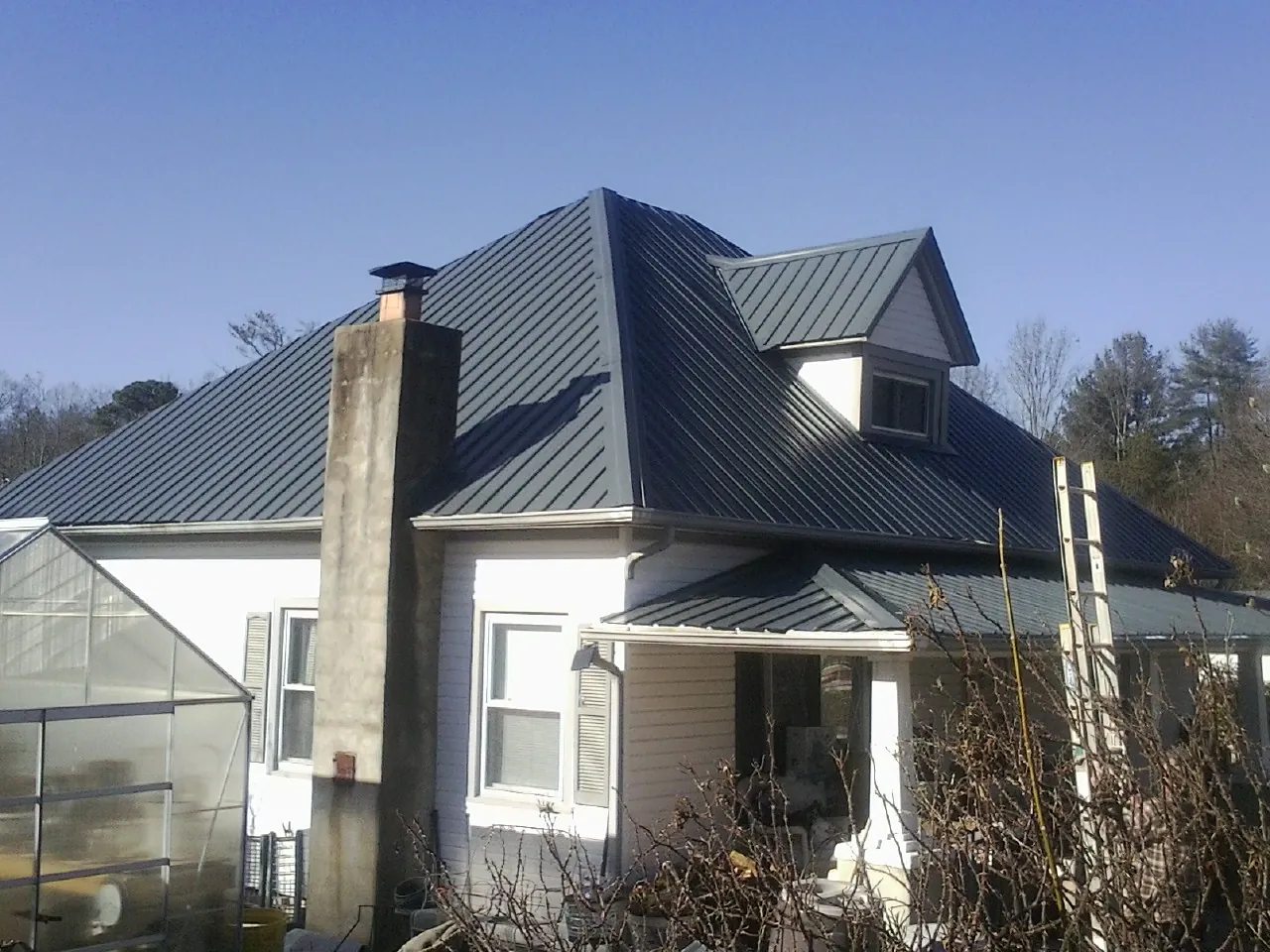 Dark blue standing seam metal roof on a white farmhouse with dormer — Slate & Tile Roof Repair by Roofing Brothers in Revere