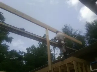 Carpenter setting a ridge beam over a new addition frame — Ice Dam Removal by Roofing Brothers in Revere