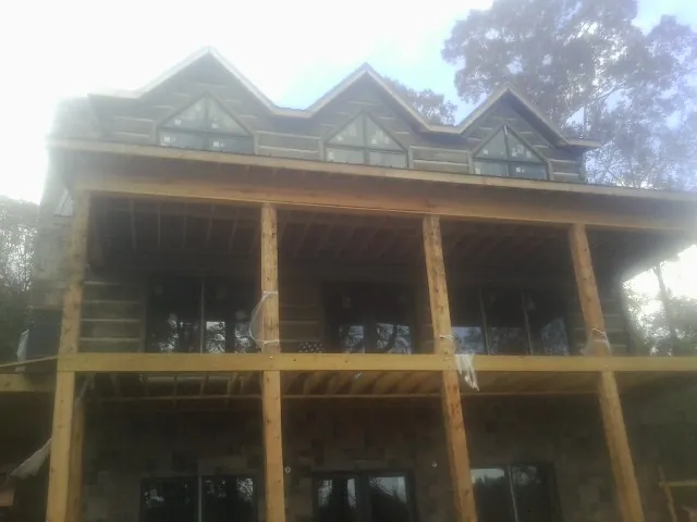 Dormers and porch framing on a large log home under construction — Roof Coating work by our crew in Revere