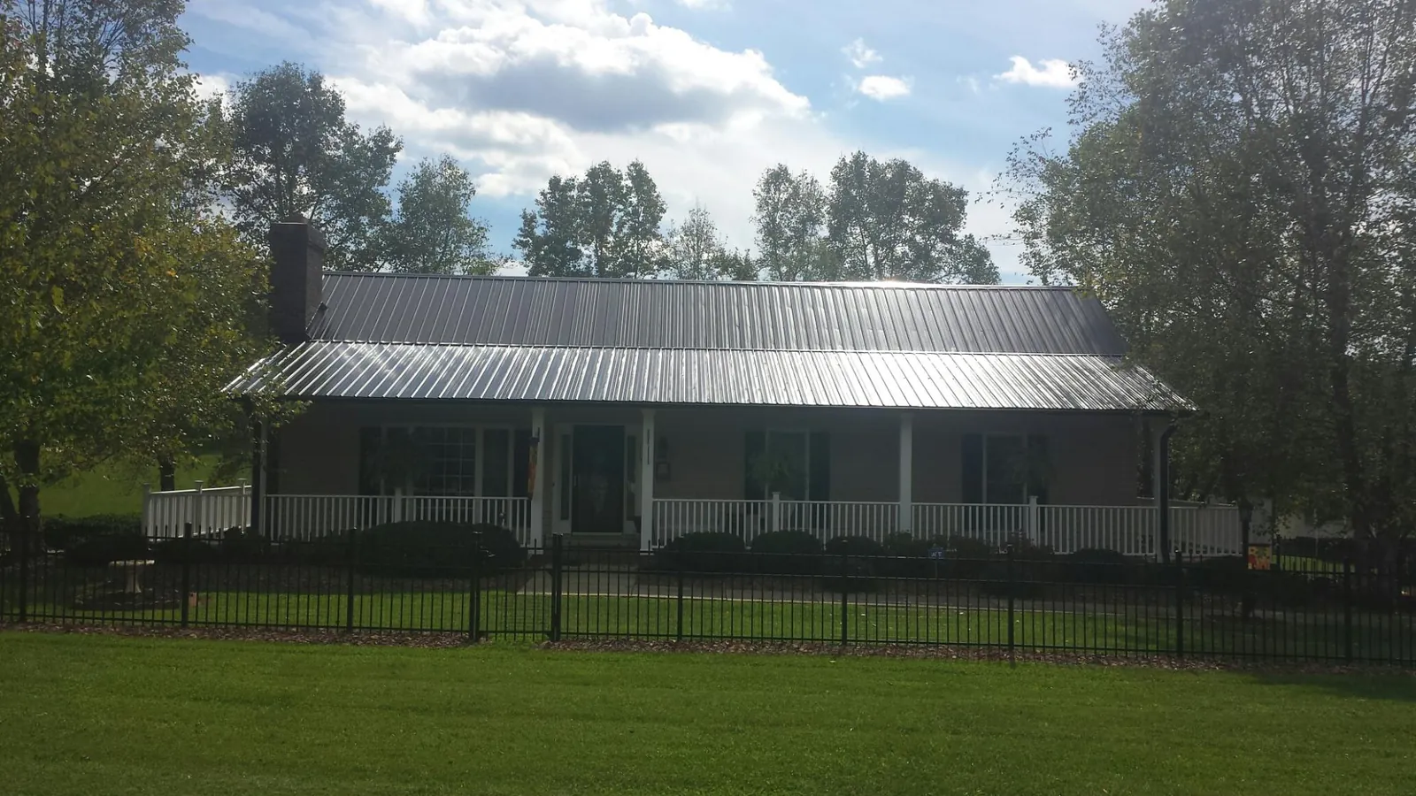 Gray metal roof on a brick ranch with a full width front porch — Gutter Guard Installation work by our crew in Revere