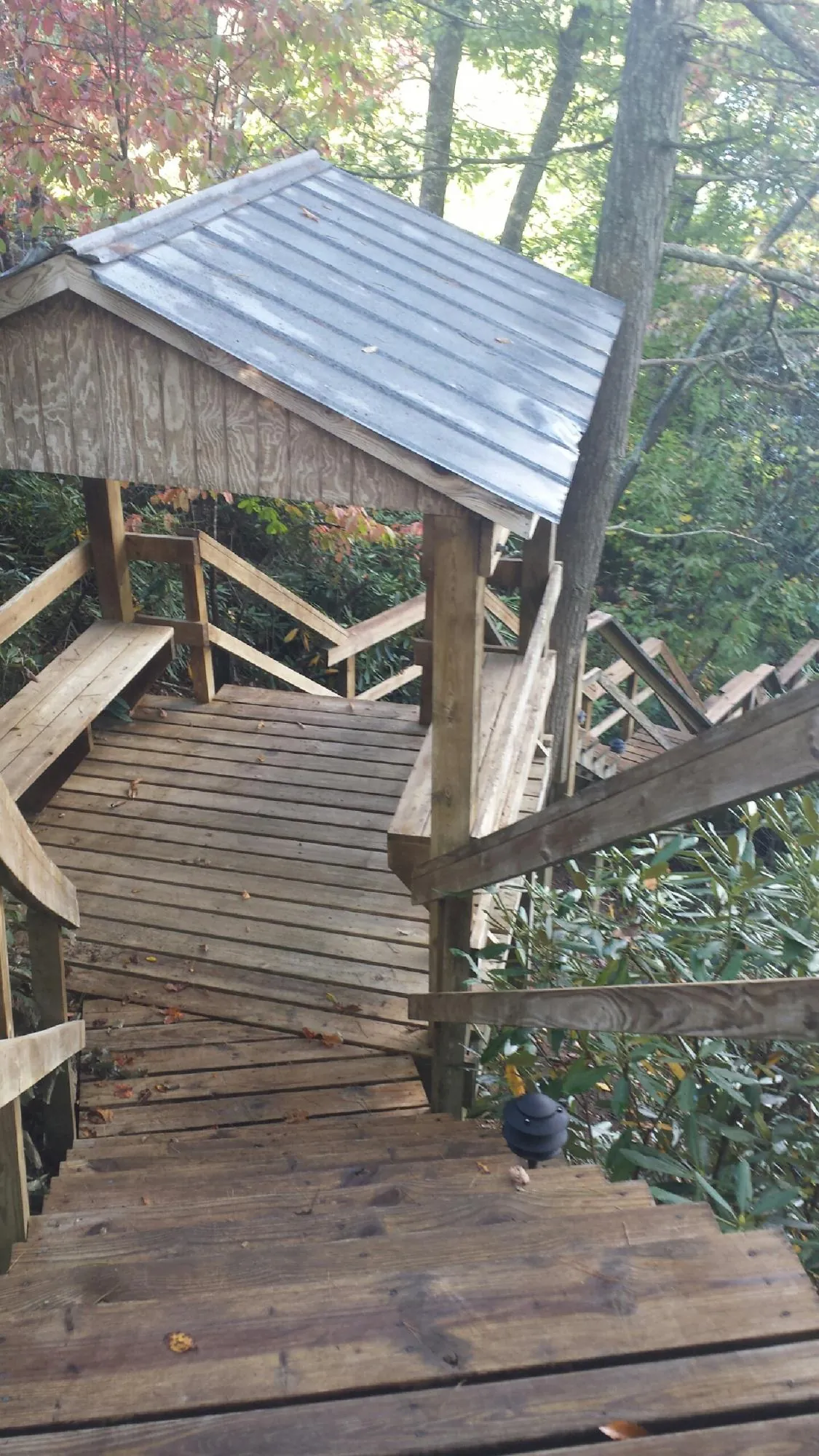 Metal roofed shelter over wooden steps on a wooded walkway — Skylight Repair & Installation work by our crew in Revere