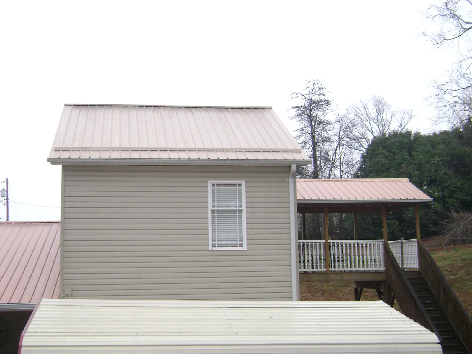 Tan metal roofs on a two story addition and attached porch, from a Roof Replacement job in Revere