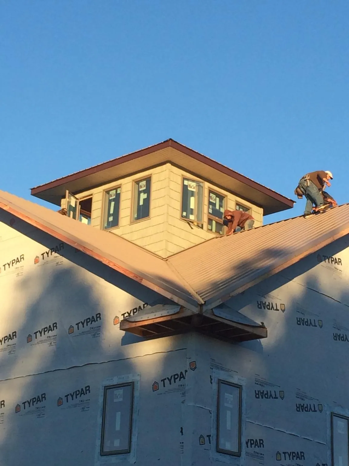 Roofers working around a rooftop cupola on a new metal roof at sunset — Roof Waterproofing in Revere by Roofing Brothers